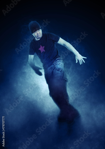 Young man break dancing on dark smoke background © Andrey Burmakin