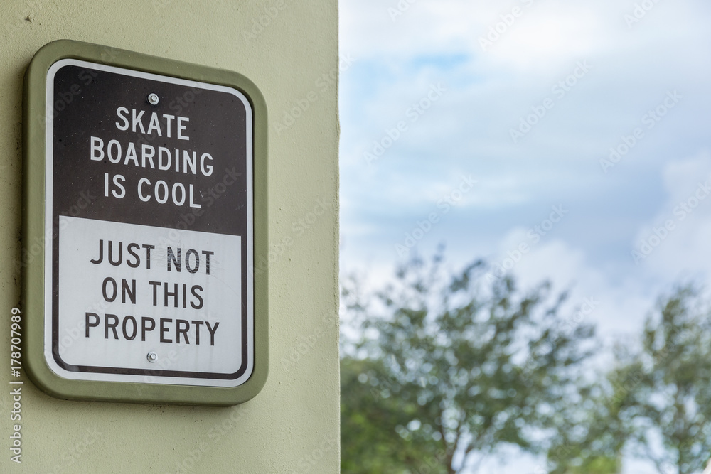 Skateboarding is cool but not here sign. an exterior sign with street background. Skateboarding is cool but not here sign. an exterior sign with street background.