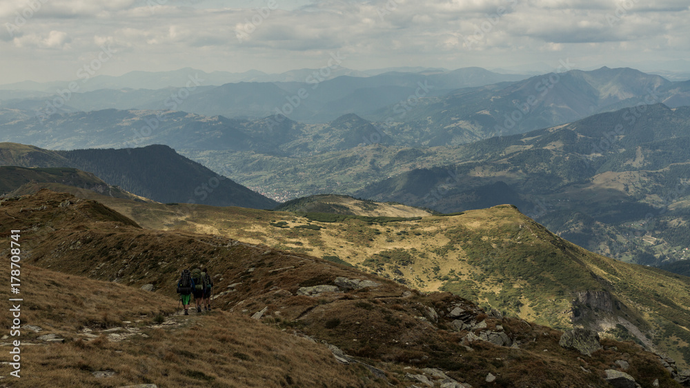 Breathtaking view on two hikers hiking over beautiful Romania country in Rodna mountain area