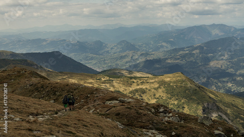 Breathtaking view on two hikers hiking over beautiful Romania country in Rodna mountain area
