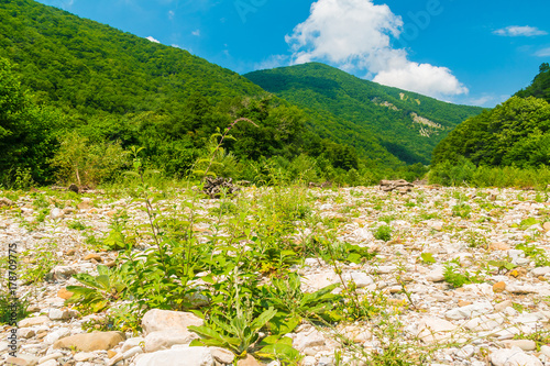 Landscape with rocky floor of ravine on the background of Tamyurdepe mountain in sunny summer day, Sochi, Russia photo