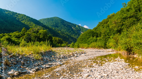 Panoramic view of Makopse river flowing in ravine on the background of Tamyurdepe mountain in the light of the setting sun, Sochi, Russia
