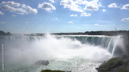 Static tri pod wide angle shot of the impressive and massive water fall Niagara Falls shot from the canadian side with boat sailing inte the mist in 4K photo