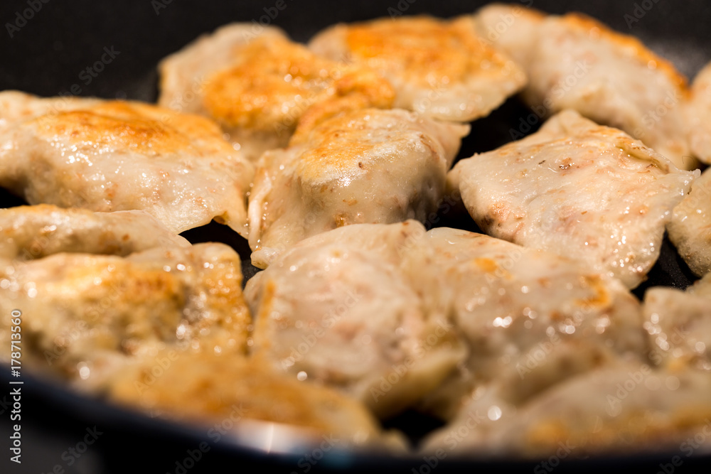 Traditional delicious Polish dumplings fried in a pan. Photography with shallow depth of field.