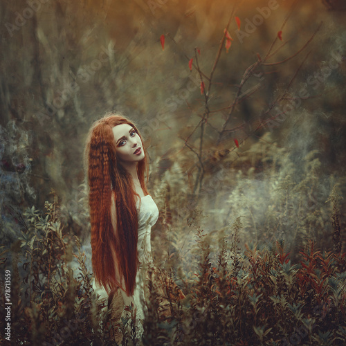 Wallpaper Mural A beautiful young woman with very long red hair as a witch walks through the autumn forest