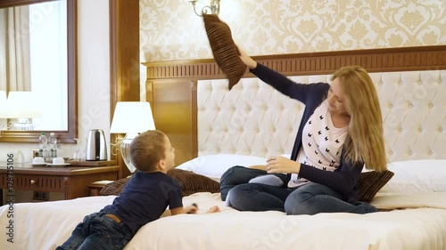 Scene Shows Young family Jumping on Bed in Room. Mom, Dad and children of European Appearance. Concept of Happy Family Life, Success, Entertainment, Advertising Hotels or Bed Linen