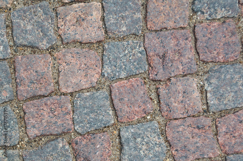 cobblestone pavement. Texture of cobblestone road close-up. Part of the road paved with red black granite.
