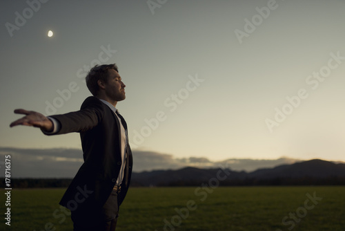 Foto Man in elegant suit standing in nature with his arms spread widely