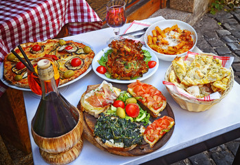 A summer  dinner .Pasta , pizza  and homemade food arrangement  in a restaurant  Rome   .Tasty and authentic Italian food.
