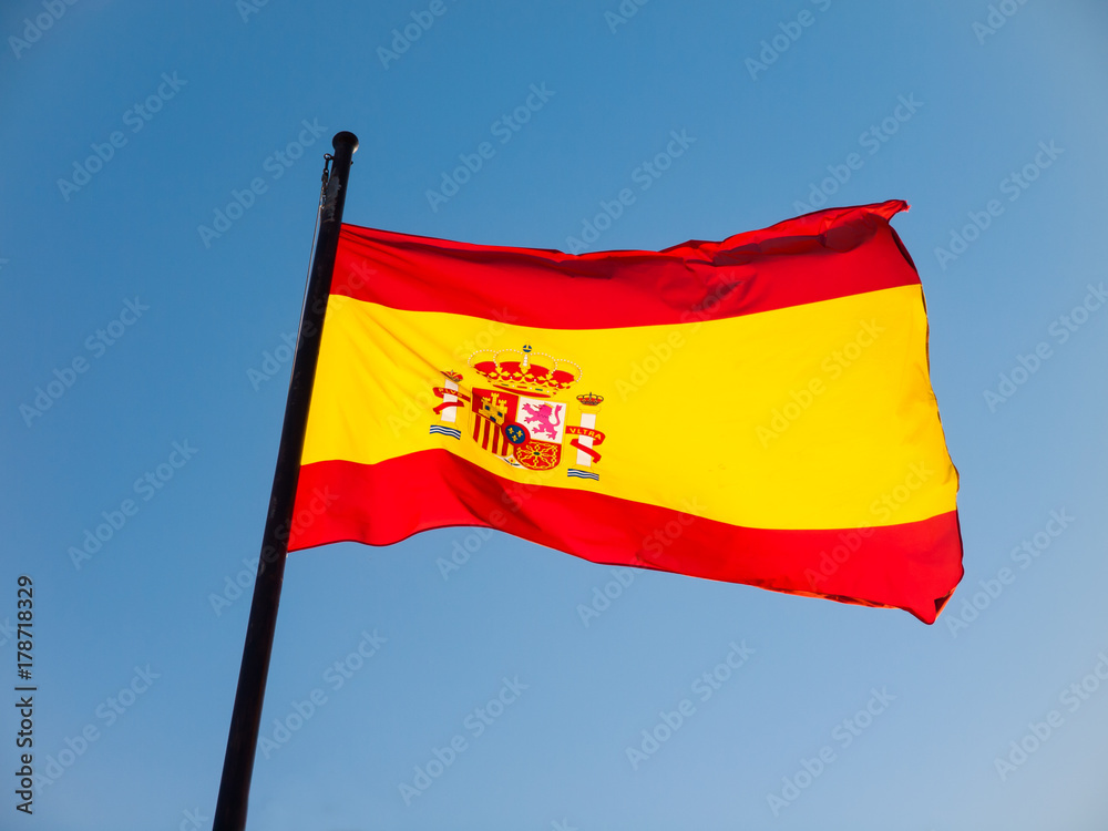 Spanish flag blowing against a blue sky at the mast Spanish flag blowing against a blue sky at the mast