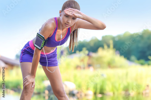 Fototapeta Naklejka Na Ścianę i Meble -  Sporty young woman resting after running in park