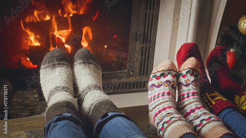 Closeup image of parents with child wearing wool socks relaxing at fireplace