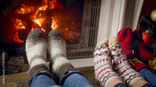 Closeup image of family with child in woolen socks warming by the burning fire