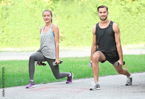 Young man and woman doing exercises in park