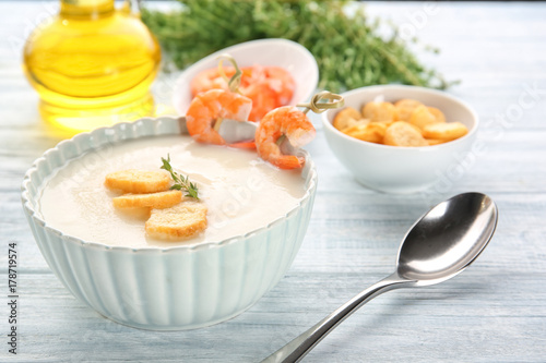 Tasty cream soup with shrimps in bowl on table