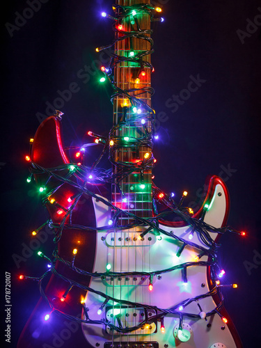 Merry christmas guitar wrapped by colorful garland as a gift background