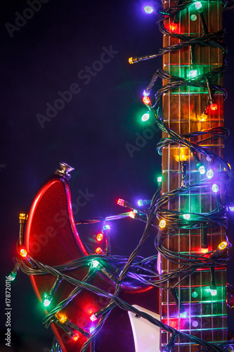 Merry christmas guitar wrapped by colorful garland as a gift background