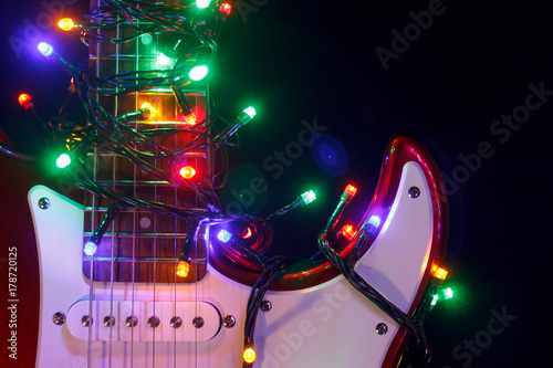Merry christmas guitar wrapped by colorful garland as a gift background