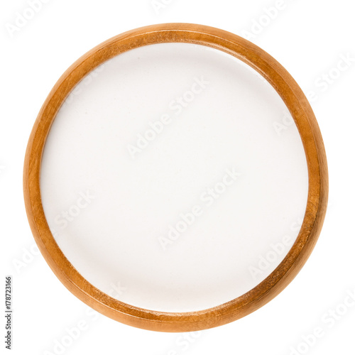 Almond milk in wooden bowl. White plant milk with creamy texture and nutty taste. Lactose free. Consumed by vegans and people who avoid dairy products. Macro food photo close up from above over white.