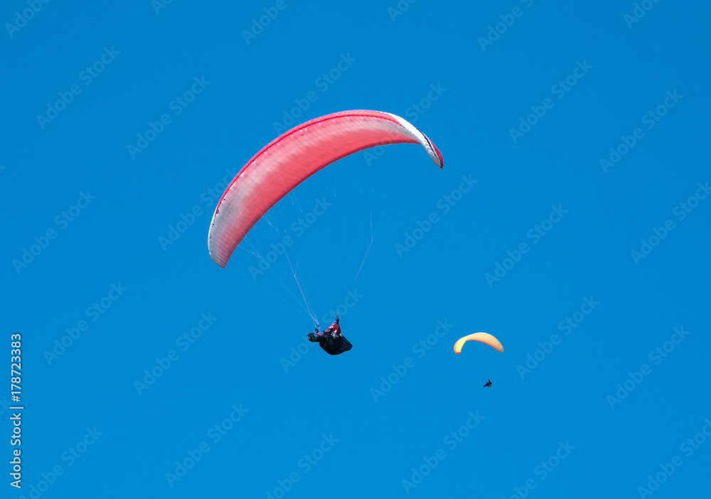 Two paragliders flies in the sky in the sunny day. Paragliding in the sky on a sunny day. Two paragliders flies in the sky in the sunny day. Paragliding in the sky on a sunny day.