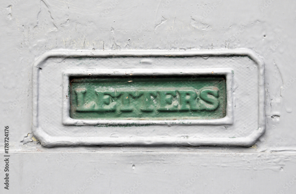 green painter mailbox in a grey house door with the word letters cast in the metal