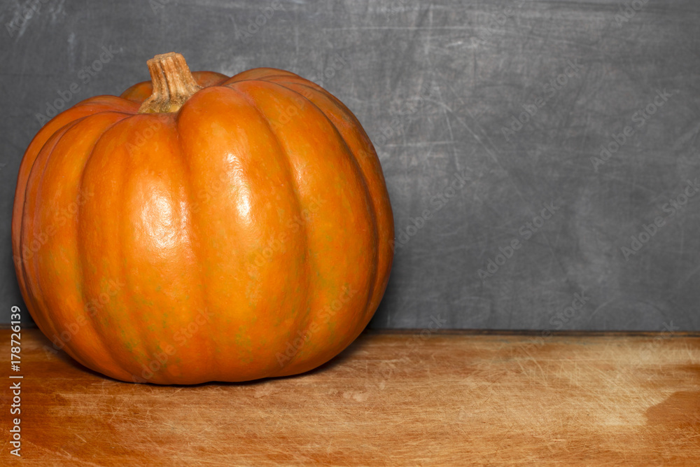 autumn pumpkin on the classroom table in front of a blackboard autumn pumpkin on the classroom table in front of a blackboard