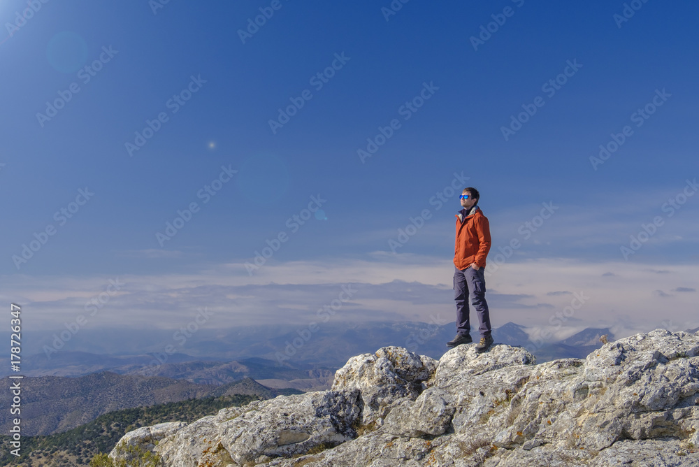 Man standing at the peak of rock mountain. Daylight