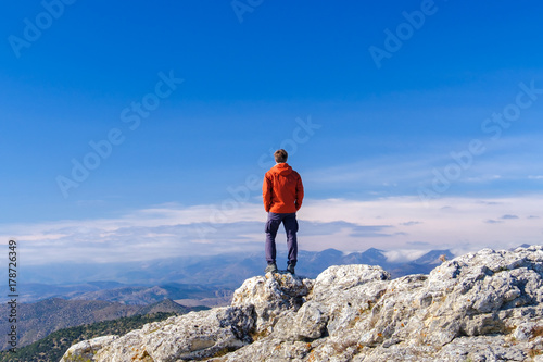 Man standing at the peak of rock mountain. Daylight