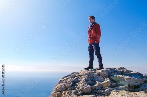 Man standing at the peak of rock mountain. Daylight