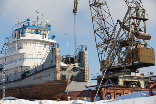 crane and  large cargo ship in winter in  backwater © Aleksei Lazukov