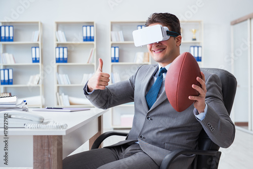 Businessman playing virtual reality football in office with VR g
