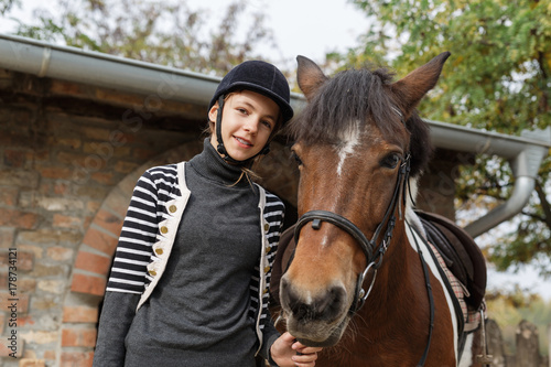  Teenage girl with her horse in front of a stable © cherryandbees