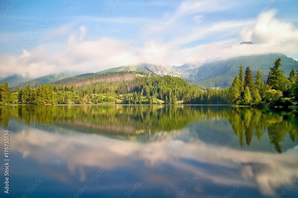 Strbske Pleso - mirroring trees on the water surface with a diving platform.