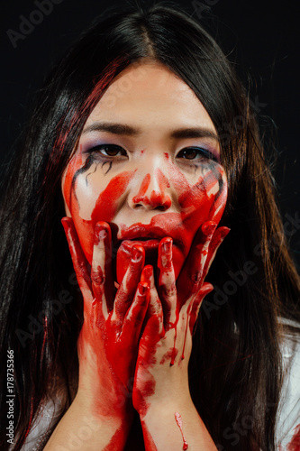 close-up portrait of a young, beautiful Asian girl on Halloween. woman covering her face bloody hand.