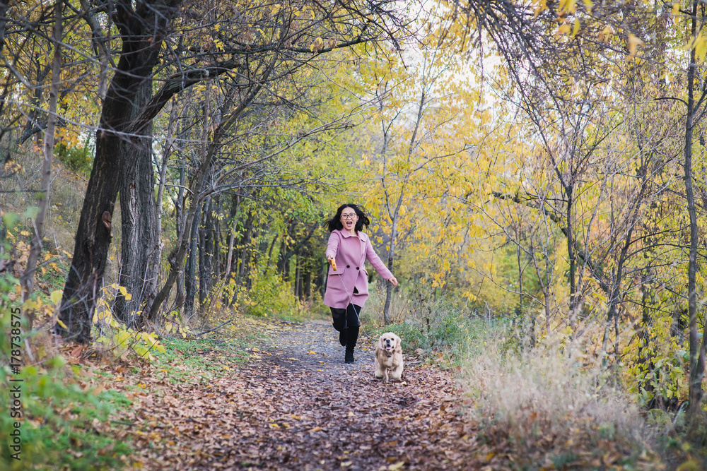 Asian girl walking with her dog in the park. A girl runs after a dog Asian girl walking with her dog in the park. A girl runs after a dog