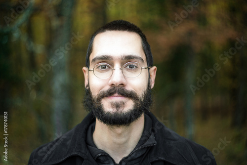 Fotografia Young Man Smiling at Camera, Enjoying Nature, Close Up Portrait, with forest gre