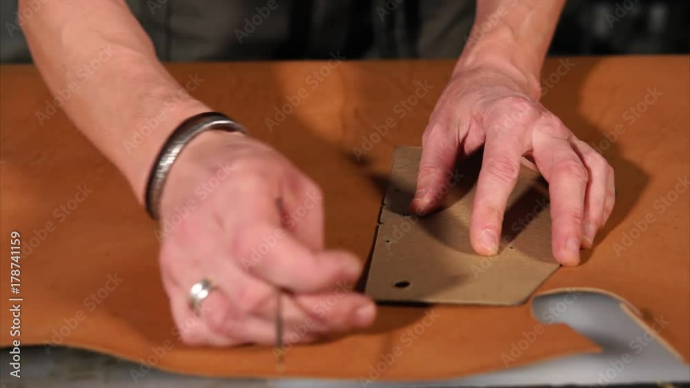 close up shot of the men's hands, who holds a template in order to make a mark on a piece of leather, the process of creating patterns for leather products close up shot of the men's hands, who holds a template in order to make a mark on a piece of leather, the process of creating patterns for leather products
