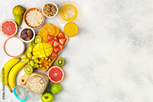 Healthy breakfast with oats, variety of fruits, strawberries, mango, grapes, figs, yogurt and nuts served on the white table, top view, copy space for text, selective focus