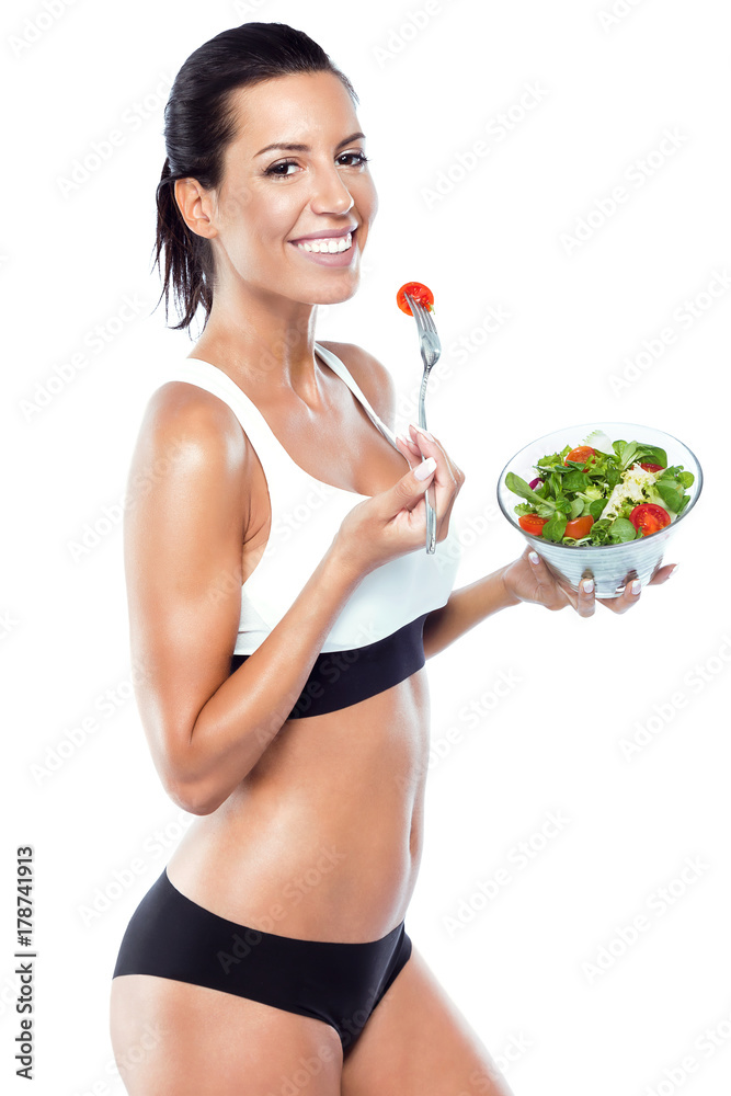 Beautiful young woman eating salad over white background. Beautiful young woman eating salad over white background.
