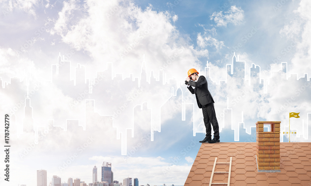 Engineer man standing on roof and looking in binoculars. Mixed media Engineer man standing on roof and looking in binoculars. Mixed media
