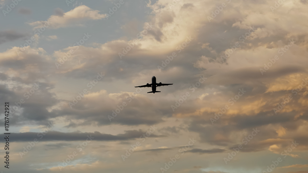 Passenger airplane taking off at sunset against the background of a very beautiful clouds.
