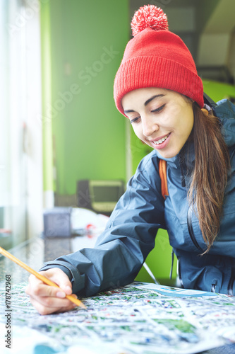 woman traveler in iutdoor clothing sitting at a table in cafe and looking at city map photo