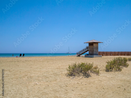 Cyprus beach in early summer with a blue sky  blue sea and sail boat on the horizon.
