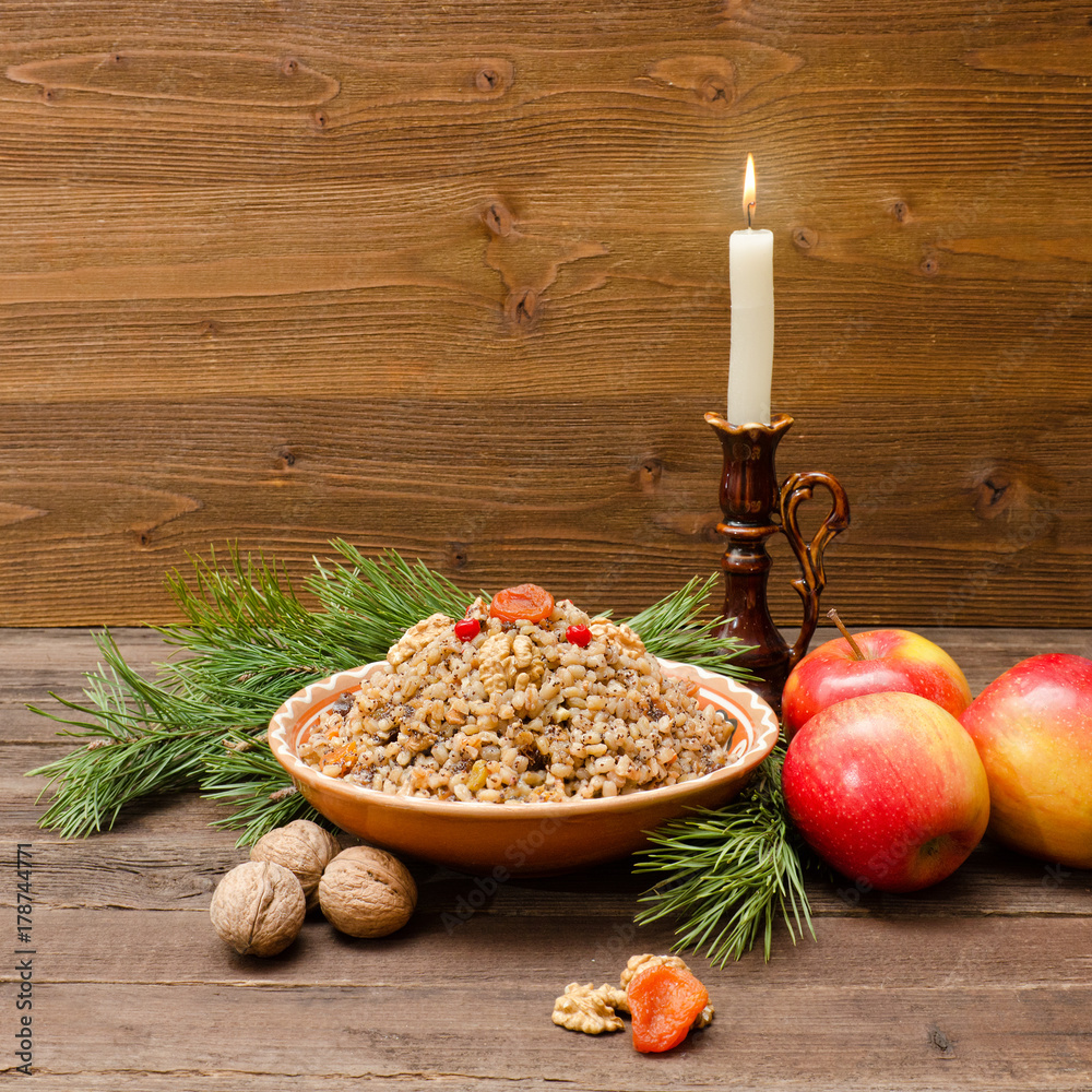 Obraz premium Plate with traditional Christmas treat Slavs on Christmas Eve. Spruce branch, apples and candle on a wooden background