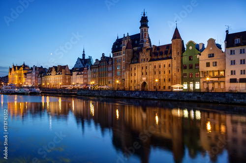 Scenic view of old buildings along the Long Bridge waterfront and their reflections on the Motlawa river at the Main Town in Gdansk, Poland, in the evening. © tuomaslehtinen