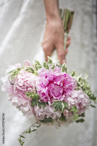 hand of the bride with a beautiful wedding bouquet of peonies