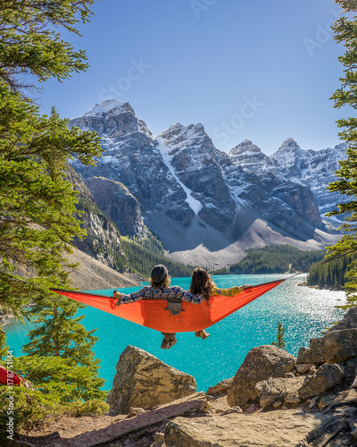 Lovers Sit in a Hammock Next to Beautiful Lake and Snowy Mountains