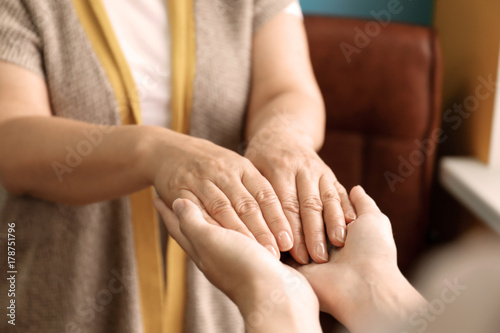 Young woman holding hands of her mother  closeup. Concept of care and support