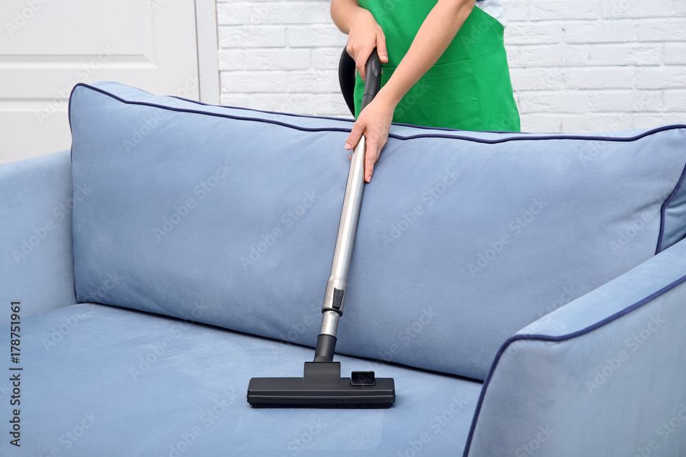 Woman cleaning couch with vacuum cleaner at home Woman cleaning couch with vacuum cleaner at home