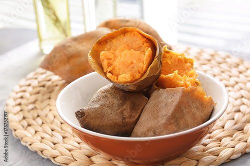 Dish with baked sweet potato on wicker mat